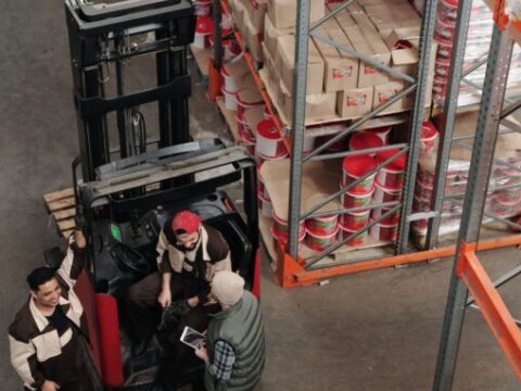 Warehouse and logistics team using two-way radios among storage racks
